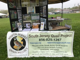 A picture of the SJQP table with a banner with the logo on it and a presentation board 